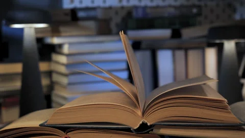 Open book with turning pages on desk in evening study environment Stock Footage 335442326