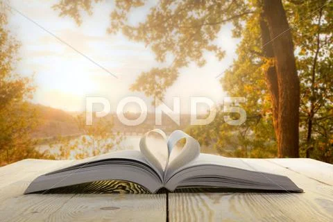 Open book at wooden table on natural blurred background. Heart books page. Back Stock Photos