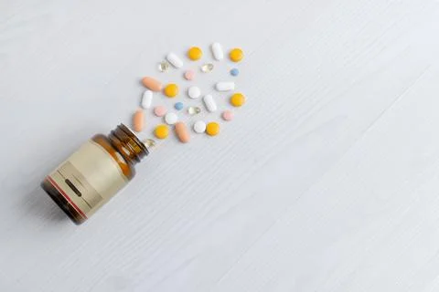 Open bottle with assorted pills spilled on clean surface, pharmaceutical an.. Stock Photos