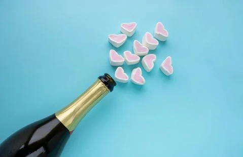 An open bottle of champagne and hearts on a blue background. Holiday concept, Stock Photos