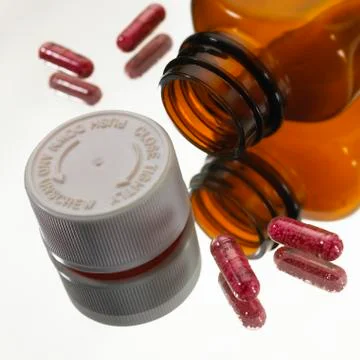 OPEN BOTTLE OF PAINKILLERS WITH TABLETS ON TABLE Stock Photos