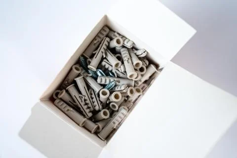 Open box filled with assorted wall plugs and screws on a white background Stock Photos