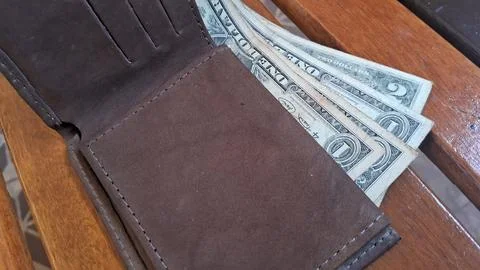 Open brown leather wallet containing several United States dollar bills inside Stock Photos