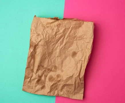 Open brown paper bag for food packaging with greasy stains on a pink green... Stock Photos