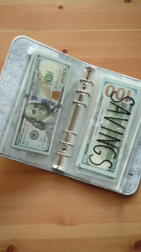 Open budget binder with savings envelope on wooden table Video stock 331772094