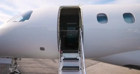 Open cabin entry door and stairway of private jet on tarmac, showcasing luxury. Stockbeeldmateriaal 313605467