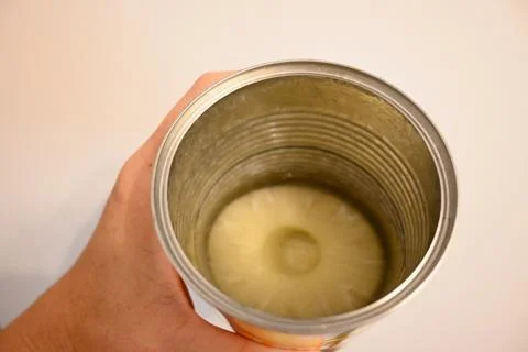 Open can of pineapple slices held by hand Stock Photos