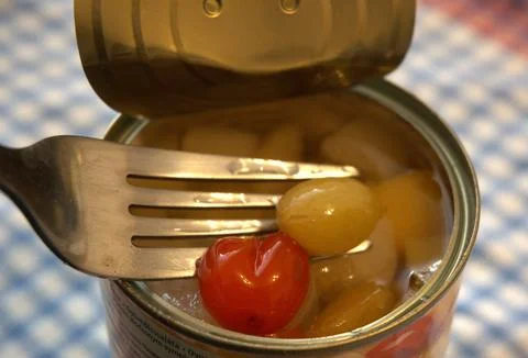 Open canned fruit salad with fork close-up Photos