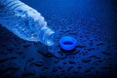 Open cap of empty platic bottle lying on dark wet floor 写真素材