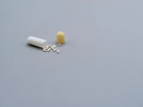 Open capsule and pellets minimal medical concept Stock Photos