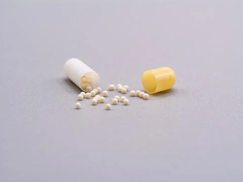 Open Capsule with White Pellets on Grey Background Stock Photos