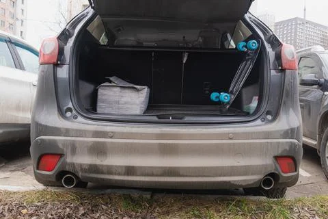 Open car trunk containing a folding suitcase and a penny board Stock Photos