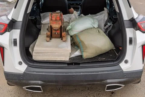 Open car trunk holds construction sacks, concrete slabs and heavy metal too.. Stock Photos