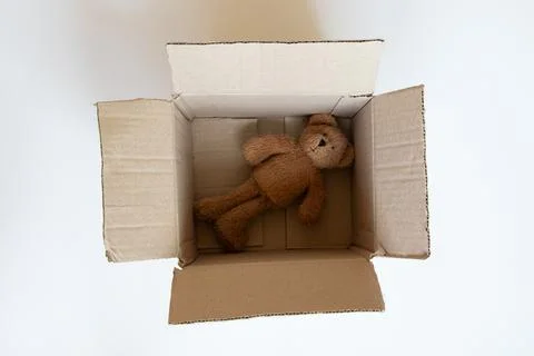 An open cardboard box with a teddy bear and wrapping paper on a white backg.. Stock Photos
