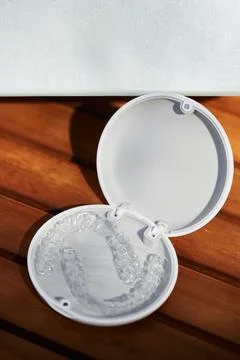 Open case with clear dental aligners on wooden table near blank box Stock Photos