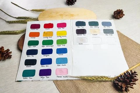 Open catalog of fabric color samples is displayed on a wooden table with ru.. Stock Photos
