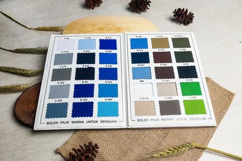 Open catalog of fabric color samples is displayed on a wooden table with ru.. Stock Photos