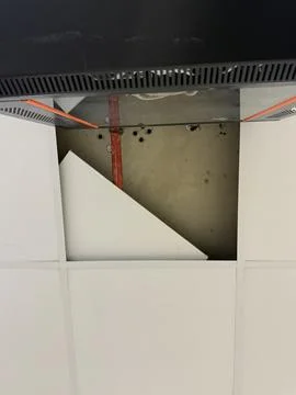 Open ceiling with removed tile, exposing pipes and dark server cabinet on t.. Stock-Fotos