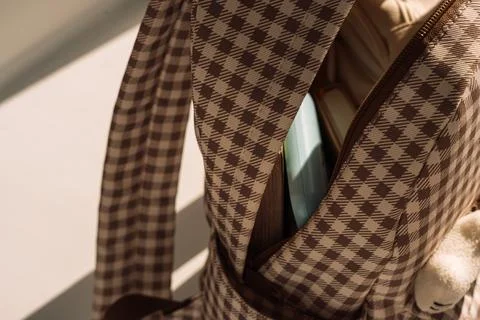 Open checkered backpack with school supplies in dramatic sunlight, back to Stock Photos