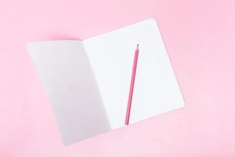Open checkered notebook with blank sheets and a pink pencil on a pink backg.. Stock Photos