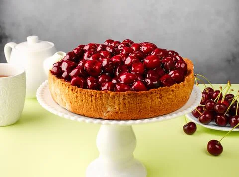 Open cherry pie on the kitchen table, on a cake pan, on a green background. T Foto stock