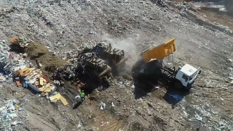 Open city garbage dump. Birds are flying, a bulldozer is leveling piles of waste Stock Footage 150017776