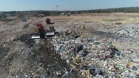 Open city garbage dump. Birds are flying, a bulldozer is leveling piles of waste Stock Footage 150018137