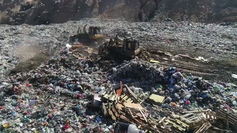 Open city garbage dump. Birds are flying, a bulldozer is leveling piles of waste Stock Footage 150018559