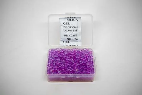 An open clear plastic container filled with purple silica gel beads and a w.. 写真素材
