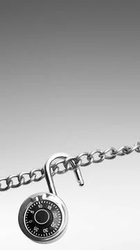 An open combination padlock hangs from a silver metal chain against a grey .. Stock Photos