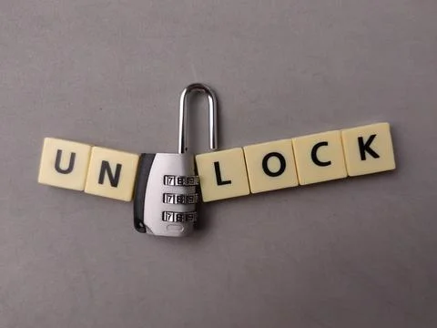 An open combination padlock sits between letter tiles spelling the word UNL.. Stock Photos