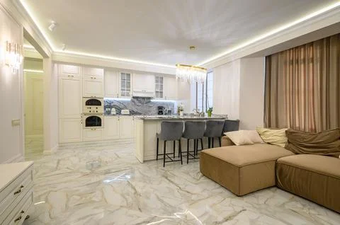 Open-concept studio apartment with classic kitchen in warm cream color and Stock Photos
