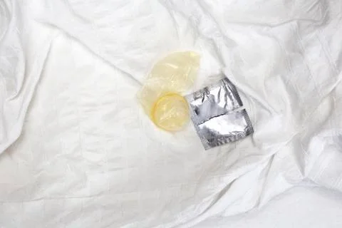 A Open condom package on white sheets of a bed, contraceptives couple relation Stock Photos