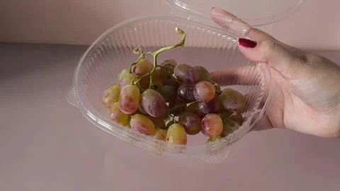 Open container of Taifi grapes in a womans hand close-up. Storing berries Stock Footage 324770034