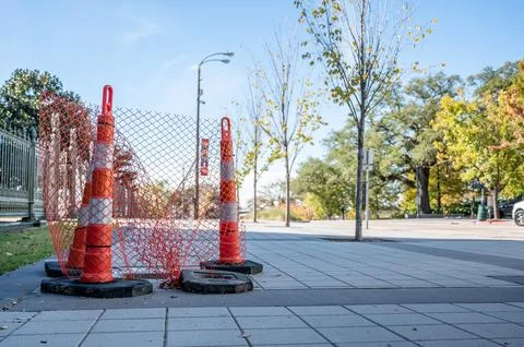 Open cover on a sidewalk access panel with hazard cones and fencing. Stock Photos