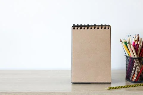 An open craft notebook with a blank page and colored pencils on the table. Foto stock