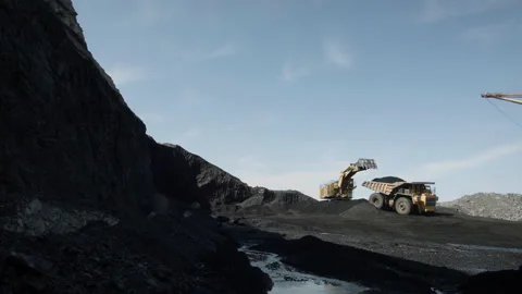 Open, deep coal pit with heavy machinery in operation against bright blue sky Stock Footage 205243929