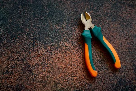 Open diagonal professional side cutters with green and orange handle on dark Stock Photos