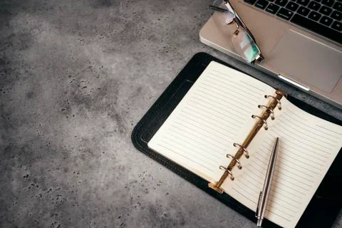 Open diary with blank sheets, laptop, pen, glasses on a gray background, copy Foto stock