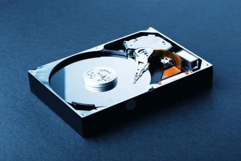Open disassembled hard disk on black plastic background. Blue Toned Image Stock Photos