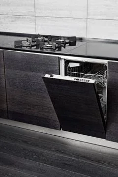 Open dish washer machine and gas-stove on black hardwood kitchen Foto stock