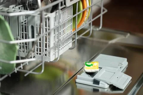 An open dishwasher in a kitchen wit a cleaning pillow on it Stock Photos