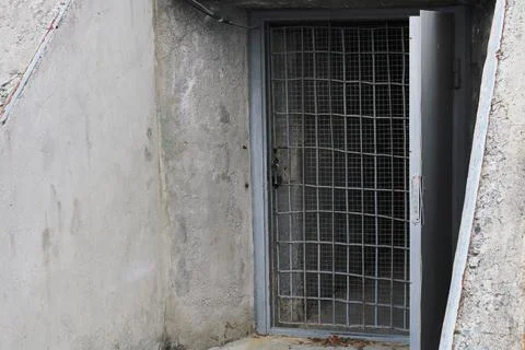 Open door to the cellar with bars in an old stone building. Stock Photos