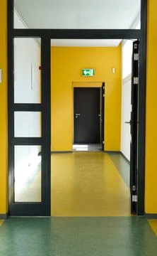 Open door leading into an empty yellow corridor of a public building Foto stock