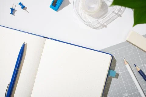 Open dotted notebook with blue pen, pencils, eraser, ruler, tape, sharpener.. Stock-Fotos
