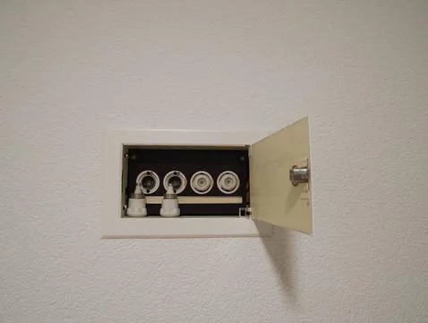 Open electrical fuse box with ceramic screw fuses mounted on a white wall 스톡 사진