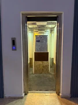Open elevator with lit ceiling and steel doors inside a building. Transport.. 스톡 사진