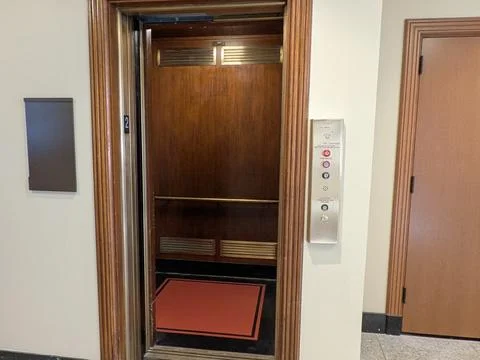 Open elevator with red carpeting and polished metal controls Foto stock