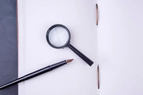 Open empty book hand-bound with magnifying glass and fountain pen Stock Photos