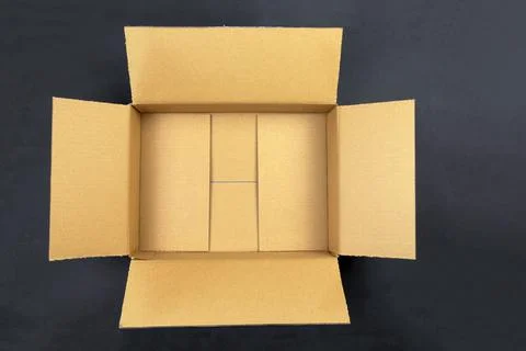 Open empty brown cardboard box on black background. Delivery, packaging Stock Photos